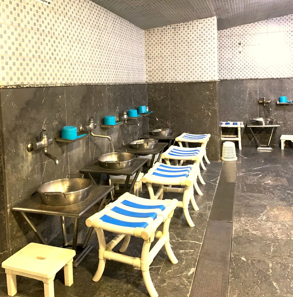 Rangée de tabourets rayés bleu et blanc devant les bassines du hammam
