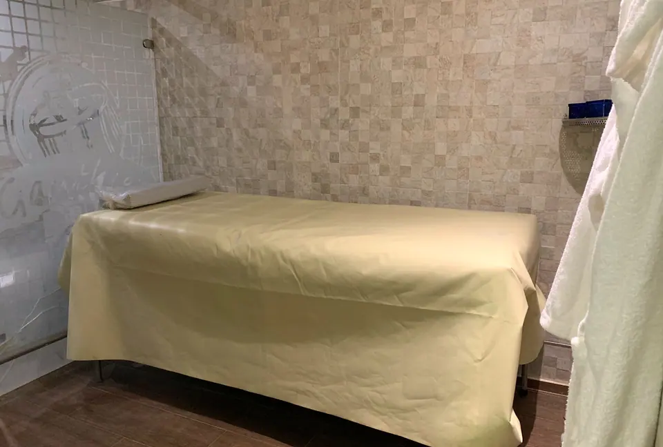 Table de massage, mur en pierre et peignoir blanc