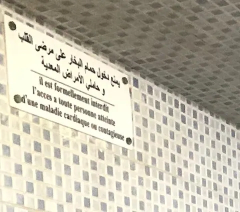 Plaque bilingue arabe et français affichée dans le hammam