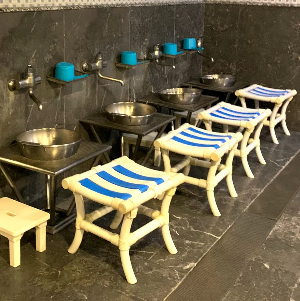 Tabourets rayés bleu et blanc et bassine en inox, dans la salle de lavage