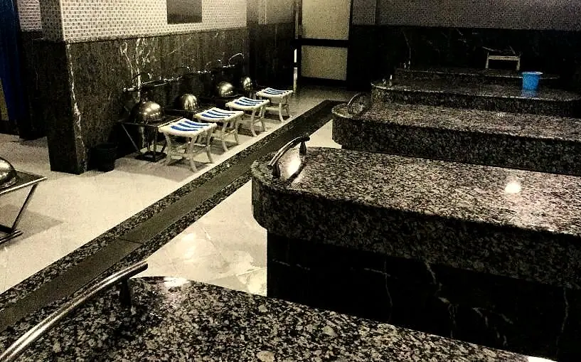 Salle chaude : banquettes de gommage en granit et bassines